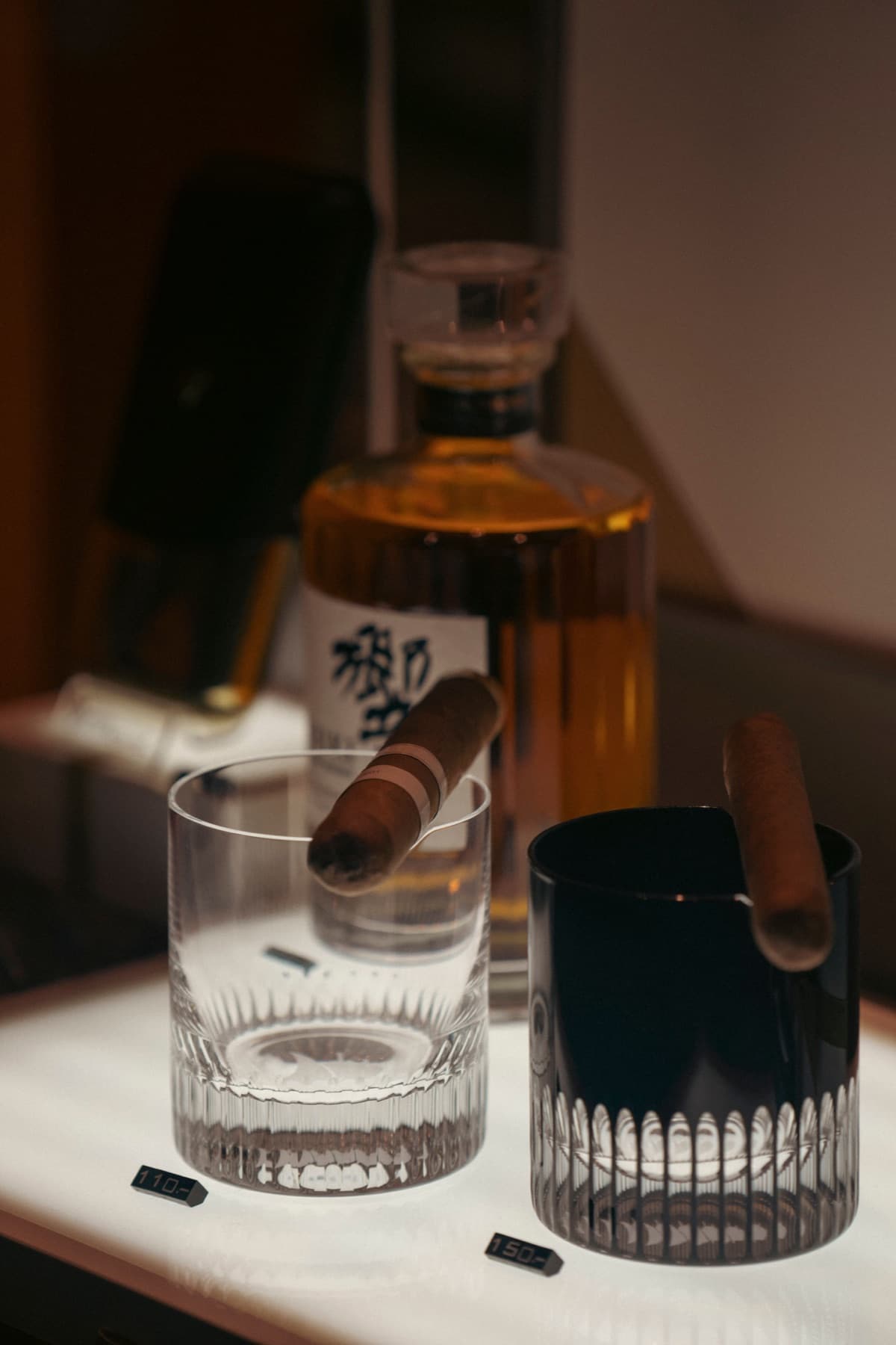 A cigar, glassware, and whiskey arranged for an evening at The Bay