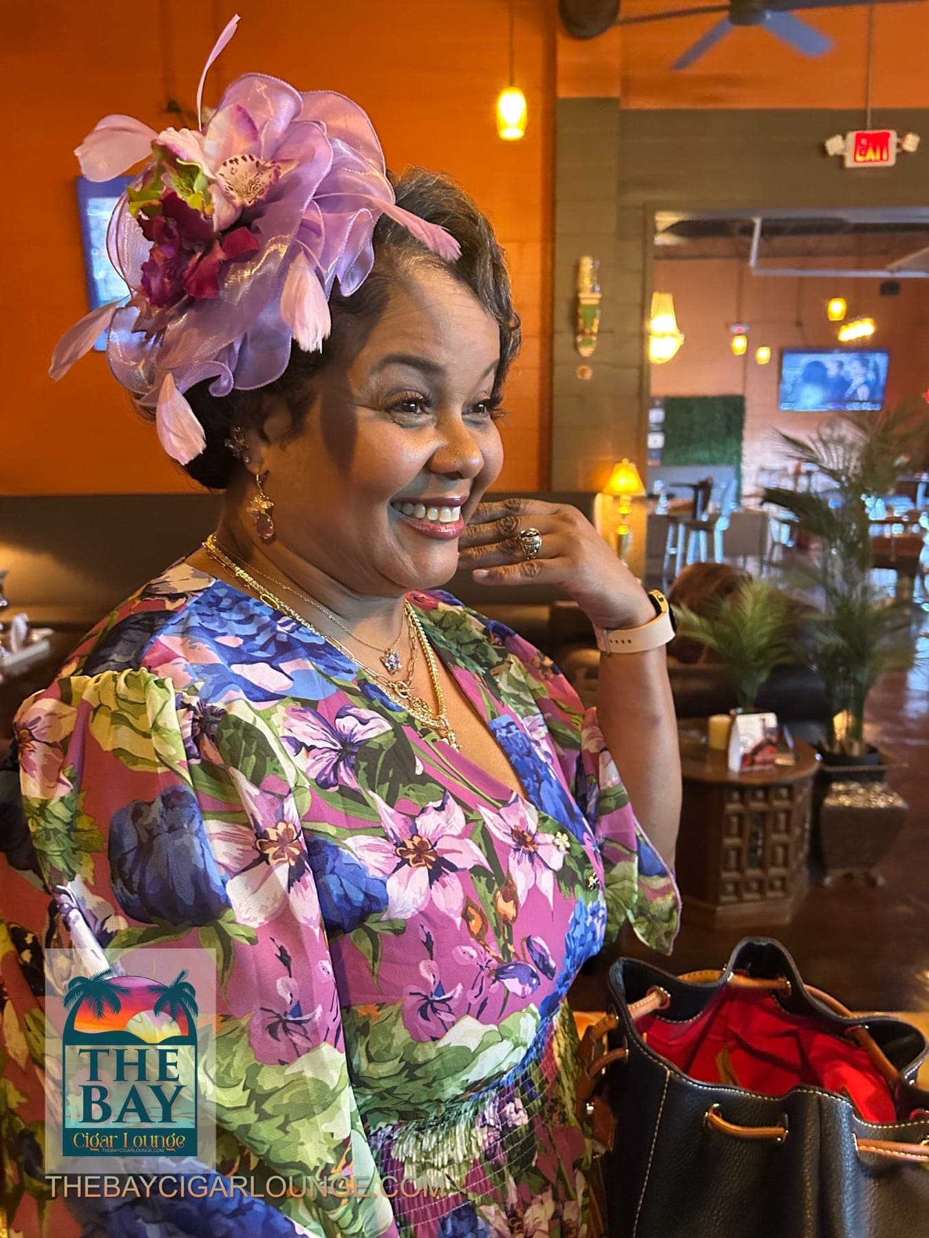 A guest in a colorful floral dress smiling inside the lounge