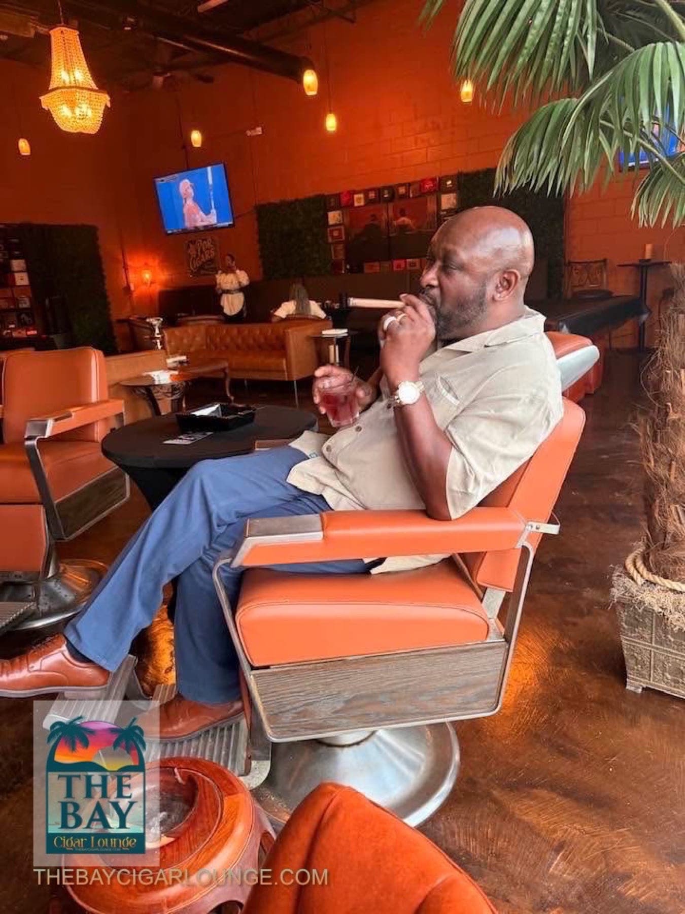 A guest relaxing with a cigar and drink at The Bay