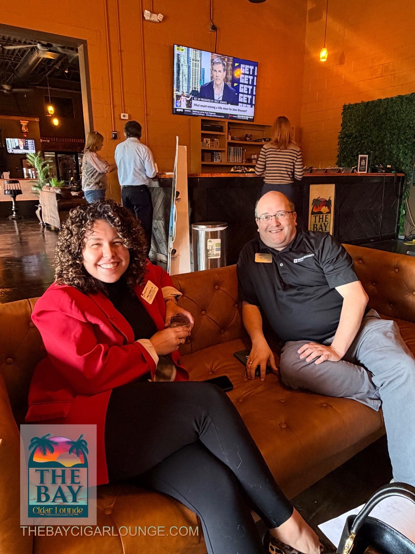 Two event attendees seated on a leather sofa at The Bay